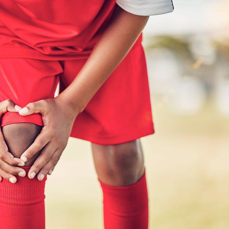 Sport, knee injury and soccer player on field, fitness and athlete have pain with exercise and medi.