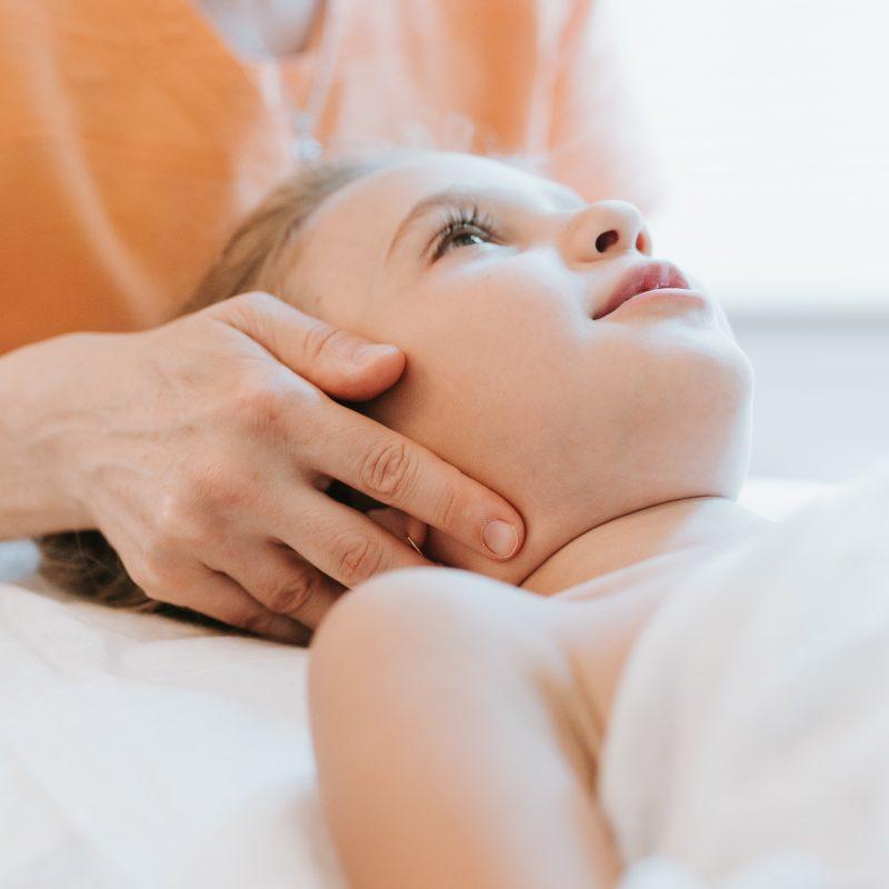 real doctor osteopath hands does physiological and emotional therapy for eight year old kid girl. pediatric osteopathy treatment session. alternative medicine. taking care of the child's health