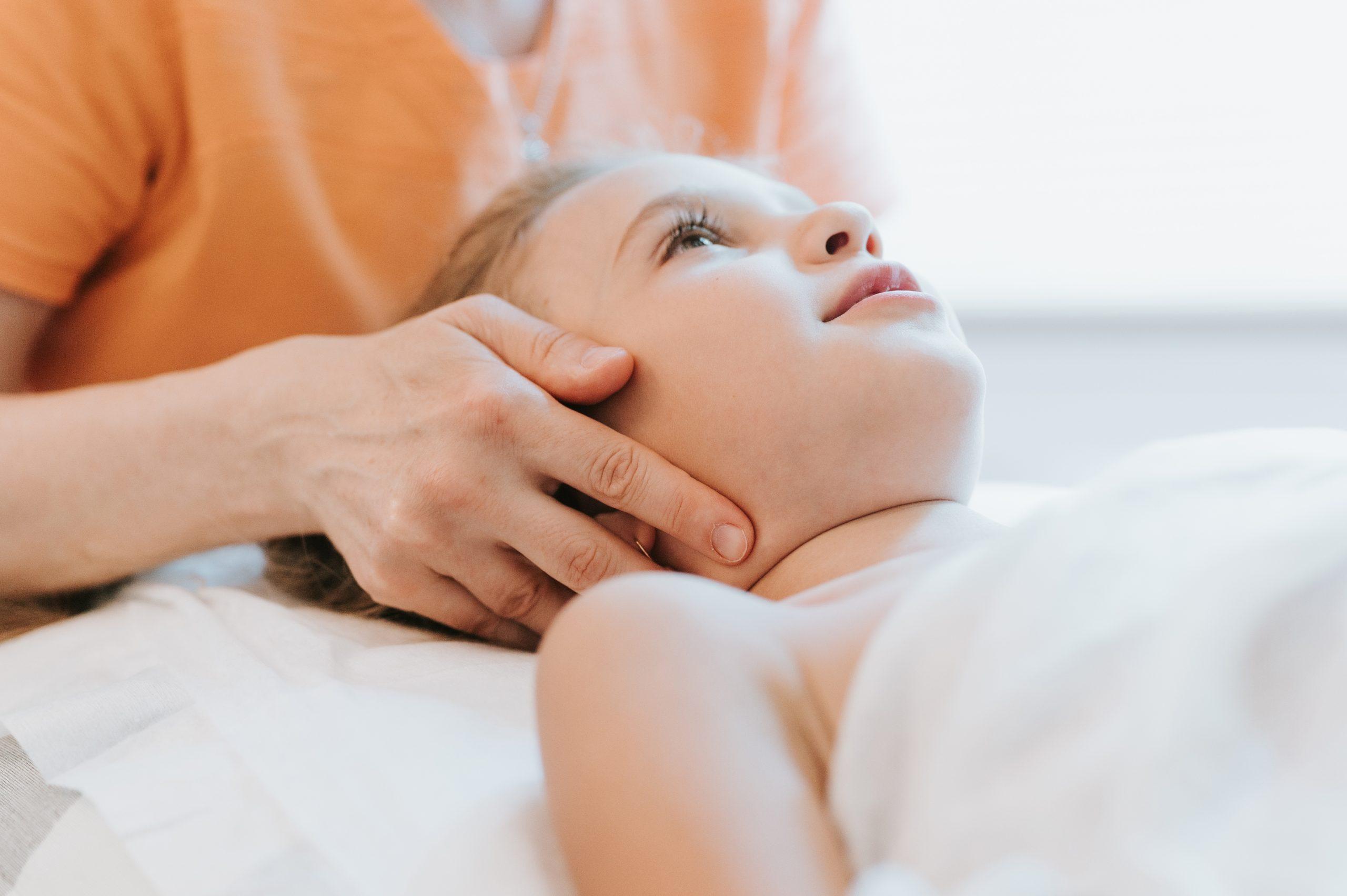real doctor osteopath hands does physiological and emotional therapy for eight year old kid girl. pediatric osteopathy treatment session. alternative medicine. taking care of the child's health